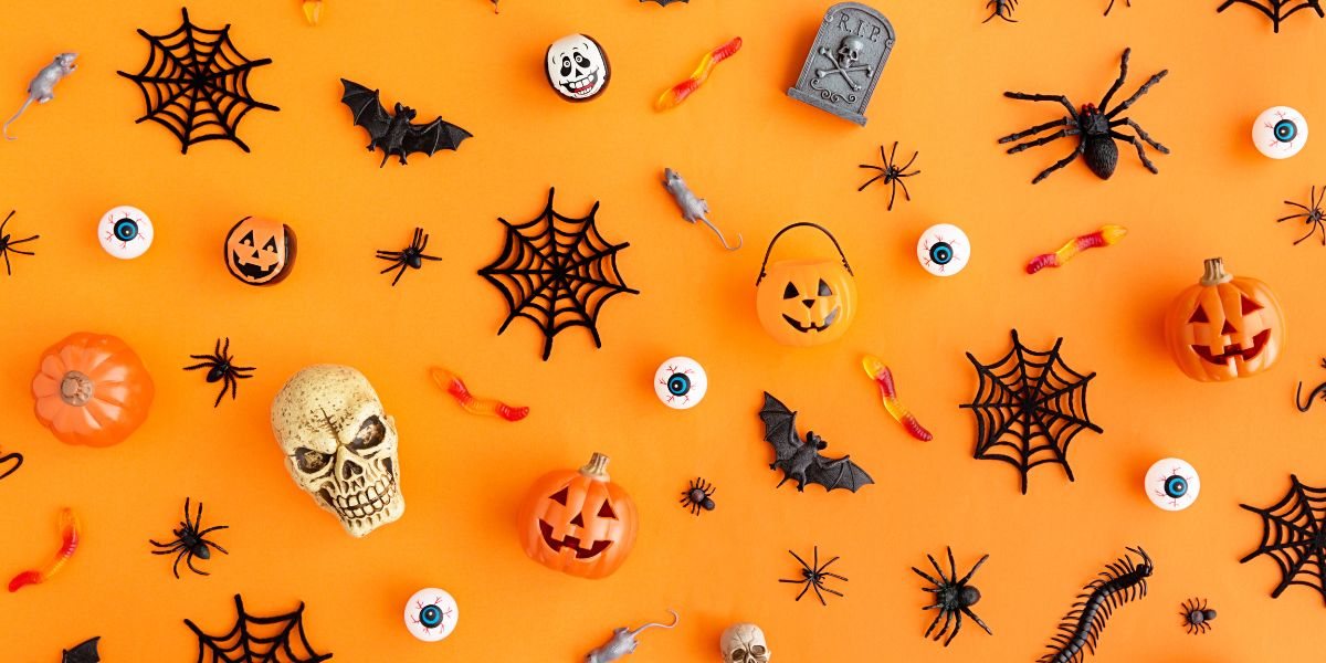 Halloweenowe dekoracje: dynie, pajęczyny, nietoperze i czaszka na pomarańczowym tle